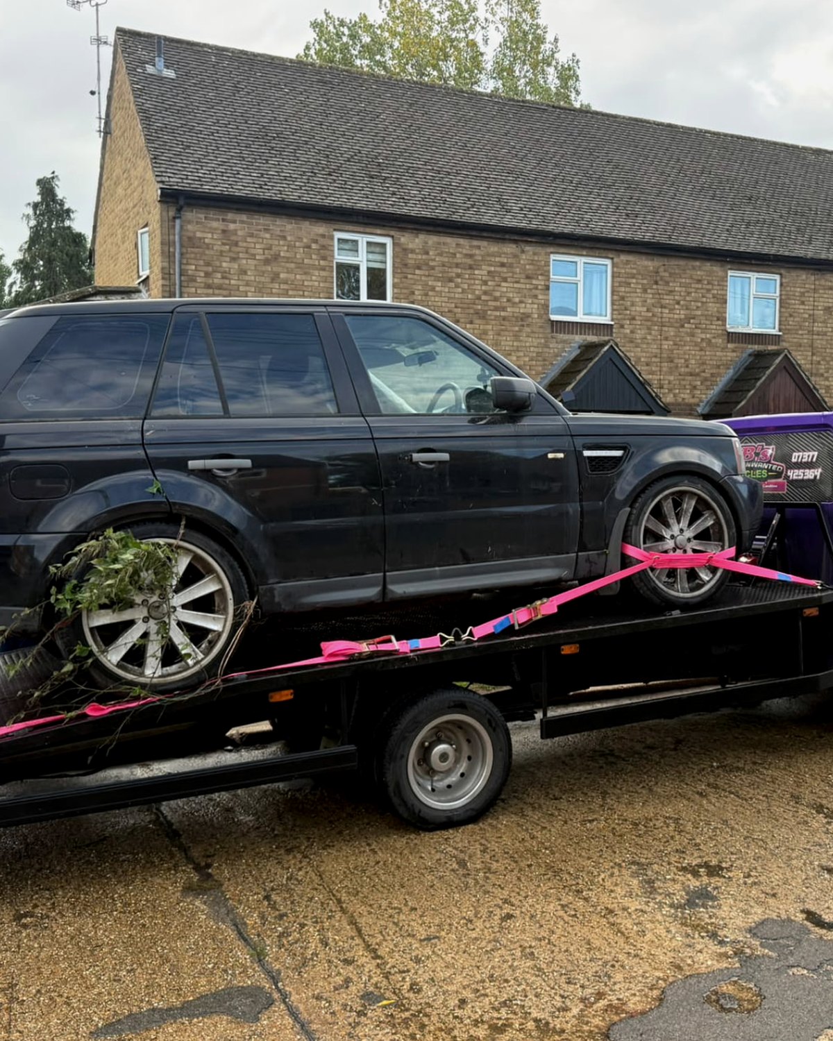 A black 4x4 strapped onto BB's purple recovery truck during a collection